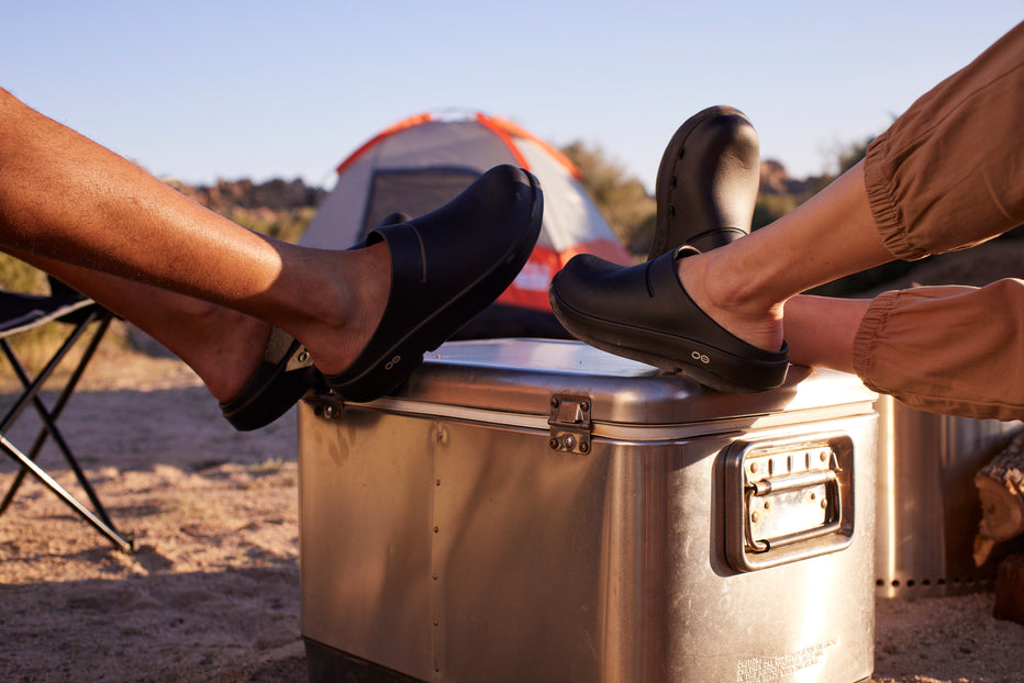 male and female models with feet on top on cooler at campsite